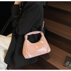 Pink crescent moon handbag with glossy finish and logo lettering shown on model