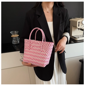 Close-up of pink and white V-pattern woven tote bag held by model in modern cafe