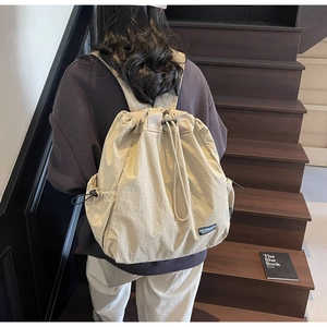 Détail d'un sac à dos en nylon beige à cordon avec poches latérales sur un escalier