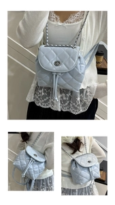Detail of light blue quilted mini backpack with metal turn-lock and chain straps