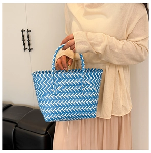 Close-up of hand-woven blue and white checkered beach bag with sturdy braided handles