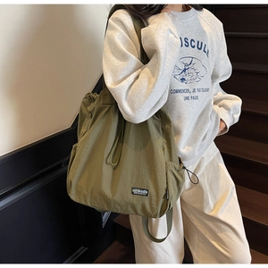 Sac fourre-tout en nylon vert olive avec cordon de serrage et poches, porté par un mannequin