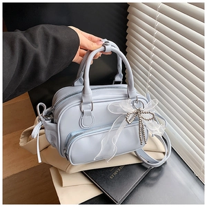 Close-up of light blue Boston bag with white lace bow and silver chain detail