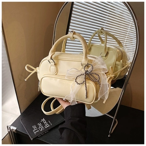 Close-up of cream yellow Boston bag with white tulle bow and silver beaded charm