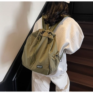 Sac à dos à cordon vert olive en tissu léger porté sur le dos du mannequin