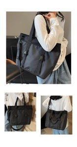 Detail view showing large capacity black nylon tote bag worn by a model in a minimalist room