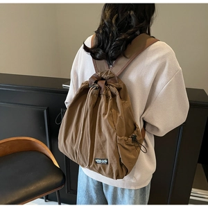 Détail d'un sac à dos marron à cordon avec un patch logo montagne et une poche latérale