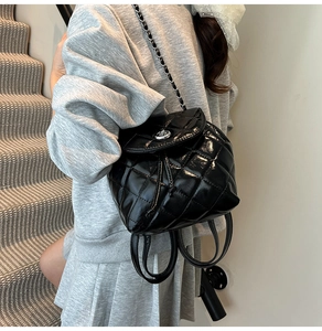 Detail of black quilted leather mini backpack with silver chain straps and turn-lock