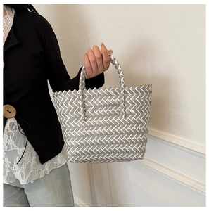 Detail of the zigzag woven pattern and cylindrical handles on a summer tote bag