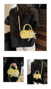 Close-up of bright yellow Boston bag with lychee grain texture and lace bow detail