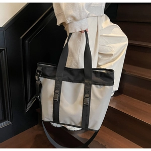 Detail of grey oxford fabric tote with black straps, plastic buckles and adjustable strap