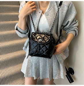 Close-up of black quilted leather backpack with silver turn-lock and chain straps