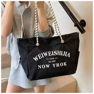 Détail d'un grand sac cabas noir en toile avec imprimé lettres et anse en corde tressée