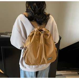Vue arrière du mannequin portant un sac à dos en nylon marron avec boucles de réglage