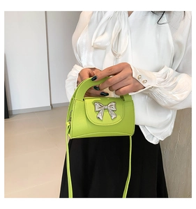 Detail of neon green leather mini crossbody bag featuring a silver metal bow buckle