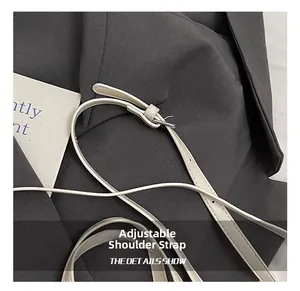 Détail de la bandoulière réglable en cuir blanc avec boucle en métal argenté poli