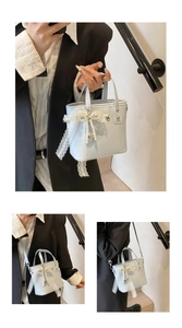 Tre viste di una borsa a secchiello azzurra con fiocco in pizzo bianco e perle