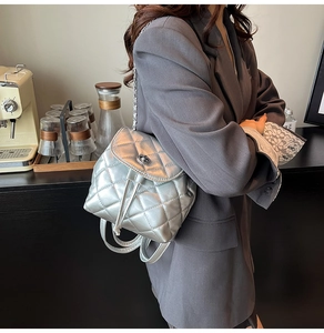 Detail of silver quilted mini backpack featuring chain straps and drawstring closure