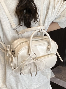 Creamy white glossy Boston bag with lace bow and pearl chain shown on model