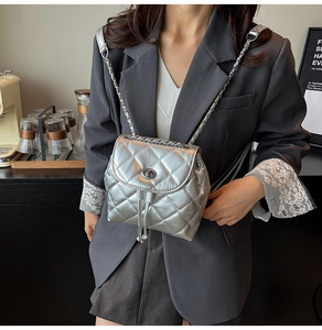 Detail of silver quilted backpack with metal chain strap and twist-lock on a model
