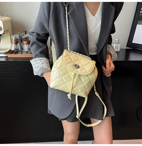 Close-up of pale yellow quilted mini backpack with silver chain strap and metal lock