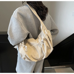 Vue latérale d'un sac cabas plissé en nylon beige porté par un mannequin en intérieur