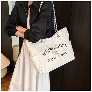 Détail du sac fourre-tout en toile blanche avec imprimé noir et anses en corde damier