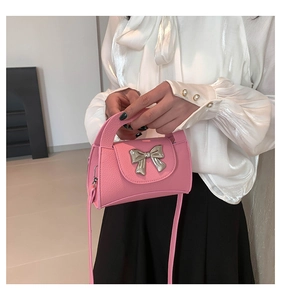 Pink lychee grain faux leather handbag featuring a large silver metal bow clasp detail