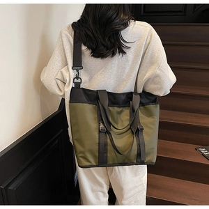 Olive green workwear tote bag with buckle details shown on shoulder in daily usage