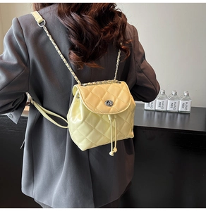 Detail of light yellow quilted chain backpack showing glossy PU leather texture and stitching