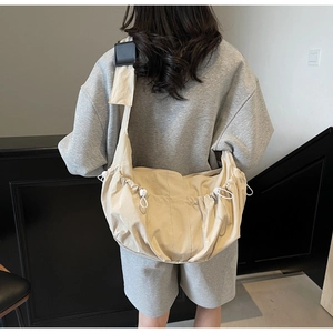 Détail du sac fourre-tout en nylon beige avec plis à cordon de serrage et large bandoulière noire