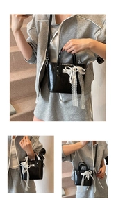 Dettaglio borsa in pelle lucida nera con pizzo bianco e ciondolo di perle eleganti