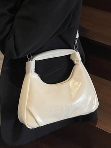 Creamy white semi-circle hobo bag with glossy finish and brand logo on wooden steps