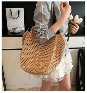 Detail of hollow woven tote bag in khaki with a thick black strap for a casual look