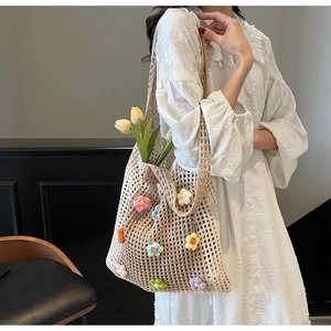 Détail du sac fourre-tout en crochet beige orné de fleurs tricotées en 3D colorées