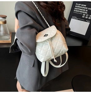 Detailed view of white quilted leather backpack with chain strap on a lifestyle background