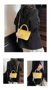Détail d'un sac jaune à texture litchi avec breloque ours et bandoulière réglable