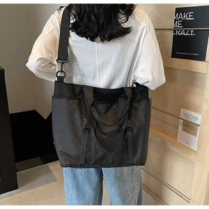 Close-up of black oxford cloth tote bag showing adjustable strap and buckle details