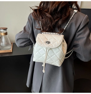 Detail of white quilted mini backpack with silver twist lock and woven chain straps