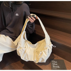 Détail d'un sac hobo plissé couleur crème avec poche latérale à cordon et large bandoulière