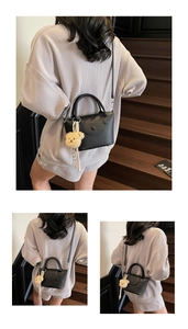 Détail du sac à main en cuir grainé noir avec breloque ours en peluche et bandoulière