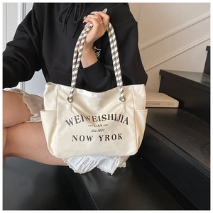 Détail d'un sac fourre-tout en toile avec imprimé et anses en corde à carreaux