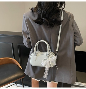 Lifestyle view of mint green bowling bag with lace bow and pearl charm on a model