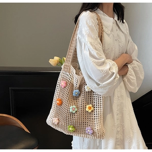 Gros plan d'un sac cabas en crochet beige avec des fleurs tricotées colorées sur une robe