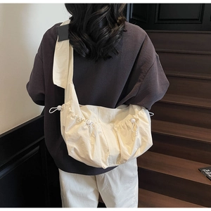 Détail du sac bandoulière en toile crème avec cordon de serrage et large bandoulière fixe