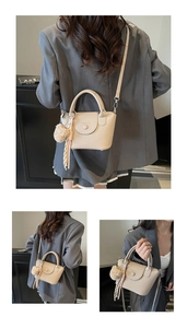 Détail d'un sac à main beige en cuir motif litchi avec pompon et décor d'écharpe en soie