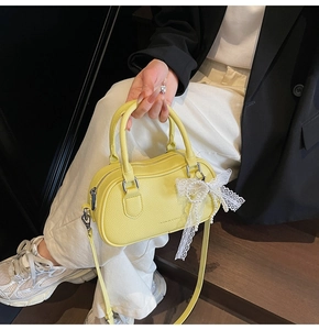 Detail of yellow Boston bag featuring pearl lace bow decoration and lychee leather texture