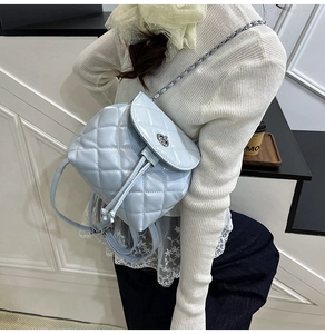 Close-up of quilted light blue backpack featuring classic chain straps and metal twist lock