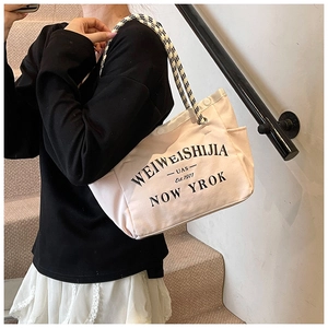 Détail du sac fourre-tout en toile avec poches latérales et anses tressées en damier