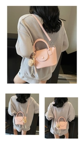 Détail du sac à main en cuir litchi rose avec un joli charm d'ours en peluche marron